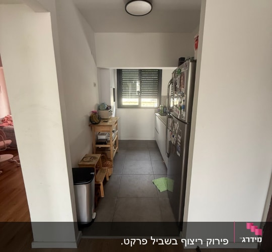 מטבח קטן עם רצפת עץ וכלי מטבח על מדפים